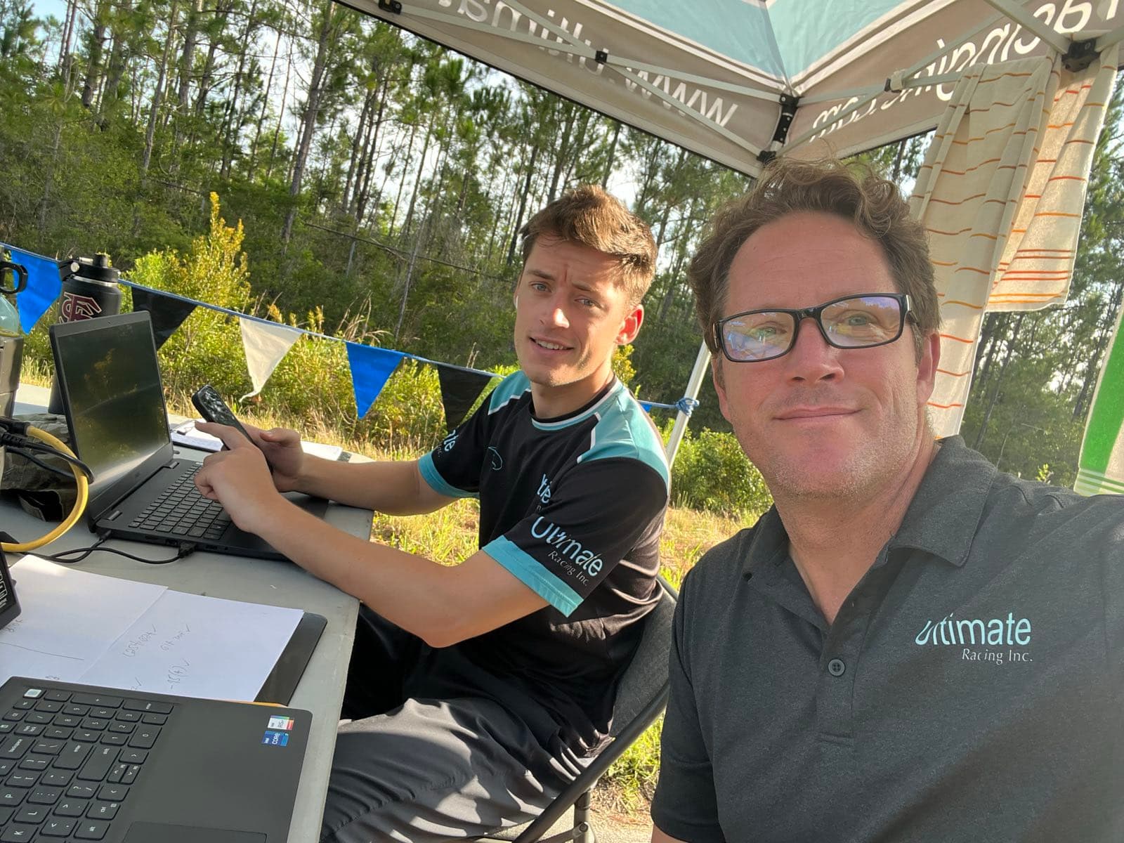 Frank Palmieri and his father Sal Palmieri working the timing table under an Ultimate Racing tent, laptops set up trackside.