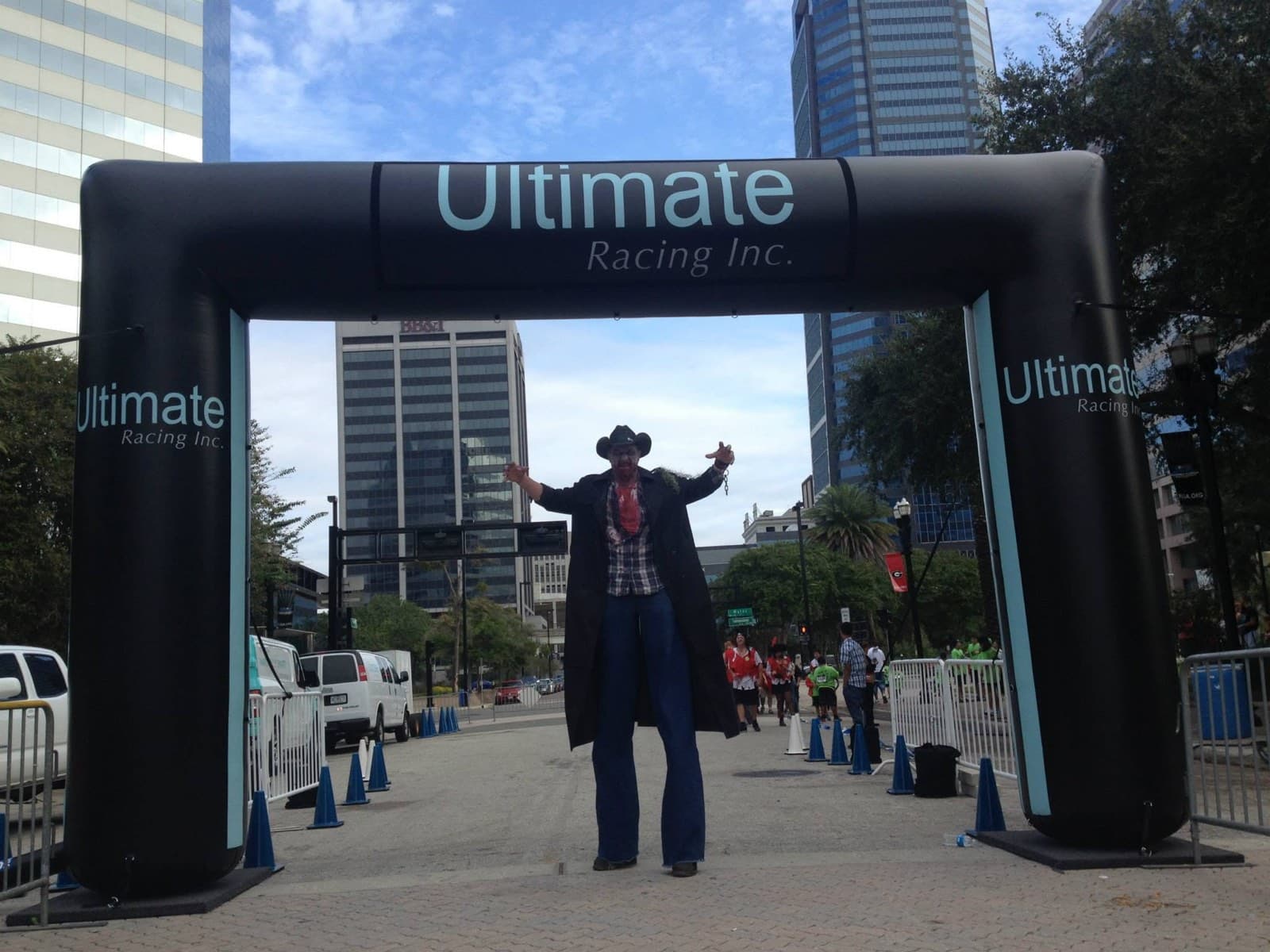 A costumed zombie performer greeting runners at a race finish arch